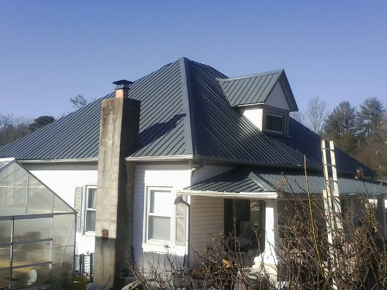Dark blue standing seam metal roof on a white farmhouse with dormer — Slate & Tile Roof Repair by Roofing Brothers in Keymar