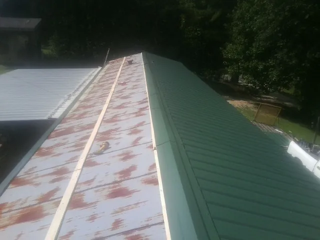 Old rusted panels beside newly installed green metal roofing — Wind Damage Roof Repair by Roofing Brothers in Keymar