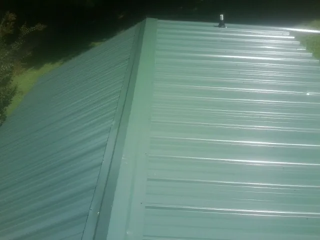 New green metal panels meeting at the ridge of a roof — Flat Roof Repair work by our crew in Keymar
