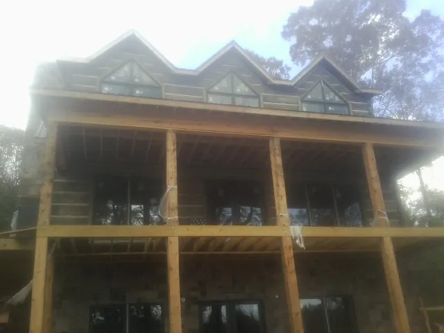 Dormers and porch framing on a large log home under construction — Roof Coating work by our crew in Keymar